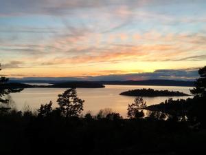 a sunset over a body of water with trees at Gjestehus 1 Solåsen in Vestby +1 photo