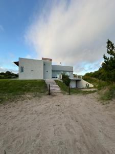 a white building on a field with a dirt road at Maura Del Mar casa de playa 4x4 in Mar Azul