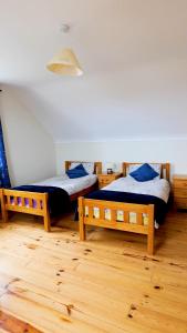 two beds in a room with wooden floors at Heather View Cottage in Carrigart +18 photos