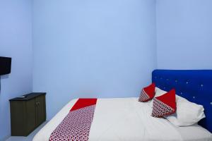 une chambre avec un lit avec des oreillers rouges et blancs dans l'établissement Hotel O Pelangi House 789 Syariah, à Nagoya