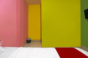 Cette chambre dispose de murs colorés et d'un lit. dans l'établissement Hotel O Pelangi House 789 Syariah, à Nagoya 16 autres photos