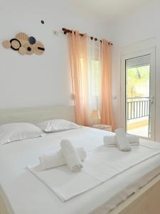 a white bed with two towels on top of it at Azalea Apartments in Sarandë