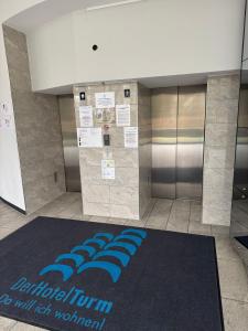 - un hall avec un tapis bleu au sol dans l'établissement Tower Suite Hotelturm Augsburg, à Augsbourg