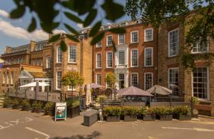 Un gran edificio de ladrillo con sombrillas delante. en Richmond Hill Hotel, en Richmond upon Thames