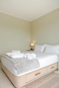 een groot wit bed met twee witte handdoeken erop bij Ocean Bliss - Beach & BBQ Apartment in Viana do Castelo
