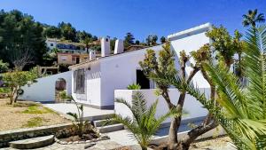 ein weißes Haus mit einer Palme davor in der Unterkunft Naranjos House in Muntanya la Sella