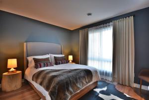 a bedroom with a large bed and a large window at Condo Luxueux au pied du Mont in Saint-Sauveur-des-Monts