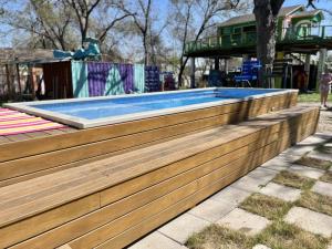 a swimming pool with a wooden retaining wall at East Side Blue Bonnet Cottage in Austin