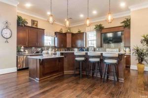 a large kitchen with wooden cabinets and bar stools at The Villas Antilia in Durham