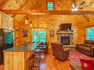 a kitchen and living room with a fireplace in a log cabin at Timber Cabin with Hot Tub and Outdoor Space in Maggie Valley