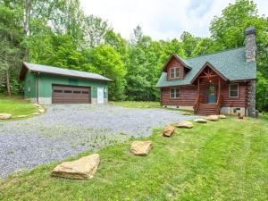 a log home with a garage and rocks in the yard at Timber Cabin with Hot Tub and Outdoor Space in Maggie Valley