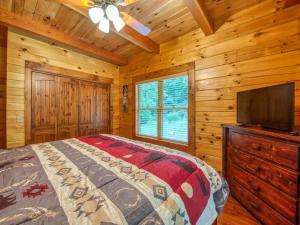 a bedroom with a bed and a flat screen tv at Timber Cabin with Hot Tub and Outdoor Space in Maggie Valley