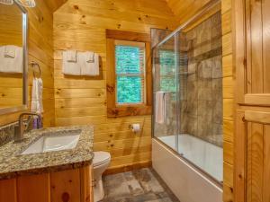 a bathroom with a toilet and a tub and a sink at Timber Cabin with Hot Tub and Outdoor Space in Maggie Valley +27 photos