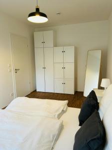 ein Schlafzimmer mit zwei weißen Betten und einem Spiegel in der Unterkunft Modernes Business-Apartment, 2 Zimmer, zentrale Lage in Hamburg in Hamburg