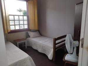 a small room with two beds and a window at Hospedaria Vó Helena in Paracatu
