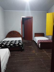 a room with two beds and a door to a bedroom at Hospedaria Vó Helena in Paracatu +3 photos