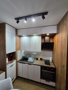 una cucina con armadietti bianchi e stufa nera di Borovi 24 a Divčibare