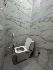 a white toilet in a bathroom with marble walls at Nature Homes 2 bhk independent Flat in Dehradun