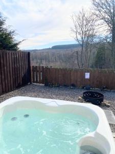 a hot tub in a yard with a fence at Kaoglen-Stags-Hot tub-Cairngorms-Pet Friendly in Balnald