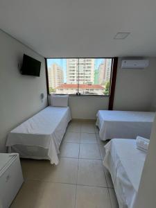 a room with two beds and a large window at Hotel Santa Catarina in Santos