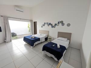 a bedroom with two beds and a large window at Pousada Costa Prestige in Touros