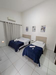 two beds in a room with blue sheets at Pousada Costa Prestige in Touros