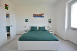 a white bedroom with a large bed with green sheets at 7th Floor - Donoratico in Cagliari