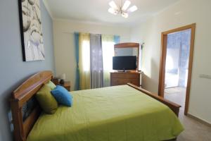 een slaapkamer met een groen bed en een televisie bij Moradia Vila Pedra in Alcantarilha
