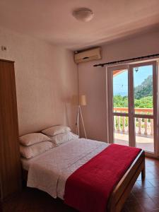 a bedroom with a bed with a red blanket and a window at Vila Marina in Buljarica