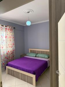 a bedroom with a purple bed and a blue light at Mateos Apartment Saranda in Sarandë