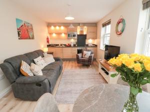 a living room with a couch and a vase of yellow flowers at Sunny Bay in Reighton +8 photos