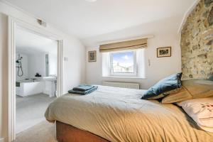 a bedroom with a large bed and a bathroom at Meads Cottage in Charmouth