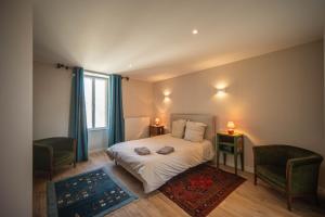 a bedroom with a bed with two chairs and a window at Gîte et studio Les Grands Crus in Morey-Saint-Denis
