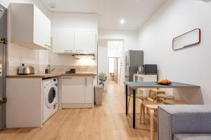 a kitchen and living room with a table and a washer at L'ARCADE SECRETE Appartement climatisé, Jacuzzi, Borne d'arcade Bordeaux centre in Bordeaux +9 photos