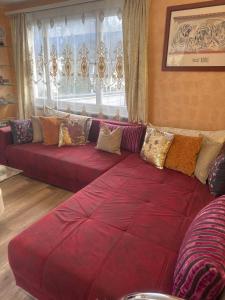 a large red couch with pillows in a living room at Bahnhof West Apartments in Interlaken +142 photos