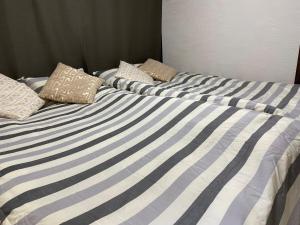 a bed with blue and white striped sheets and pillows at 子猫の家 103t in Tokyo