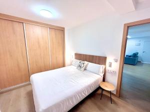 a small bedroom with a white bed and a table at Apartaments Sant Antoni in Benidorm