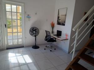 ジョアンペソアにあるCASA À 3 KM PRAIA TAMBAÚのデスク、椅子、ファンが備わる客室です。