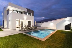 a villa with a swimming pool in front of a house at Gorvorana 3 - Piscina privada, BBQ in Realejo Bajo