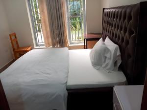 a bed in a room with a large window at Maison De Omashi in Kigali