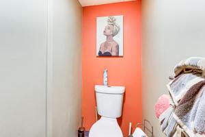 a bathroom with an orange accent wall and a toilet at 3 Mi to Dtwn New Haven Colorful Condo with Yard! in West Haven