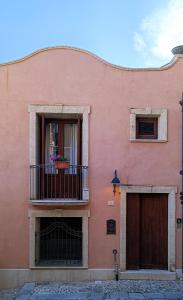 een roze gebouw met een balkon en een deur bij Casa all'Annunziata in Termini Imerese