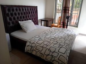 a bedroom with a bed with a black and white comforter at Maison De Omashi in Kigali