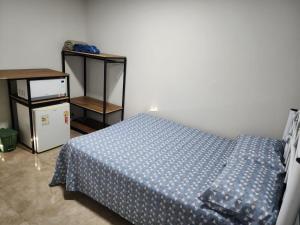 a bedroom with a bed with a blue comforter at Quarto mobiliado em Lins in Lins