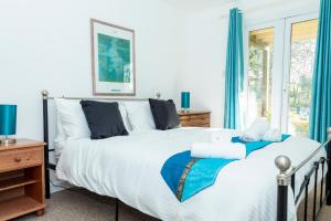 a bedroom with a bed with blue curtains and a window at Valley Lodge 40 in Callington +18 photos
