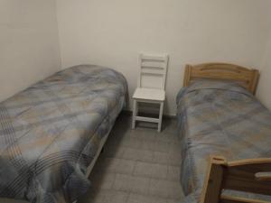 a small bedroom with two beds and a chair at Lo de Nelly 1 in Puerto Madryn