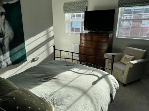 a bedroom with a bed and a tv and a chair at Sherfield Park Ensuite Room in Sherfield on Loddon