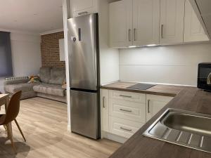 a kitchen with a stainless steel refrigerator next to a couch at Apartamento Turístico HUGO DE PILAR in Ávila