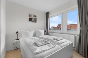 a white bedroom with a bed and a window at Haus Klaus Lucky in Norderney