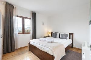 ein weißes Schlafzimmer mit einem großen Bett und einem Fenster in der Unterkunft Casa do Recanto by Sé Apartamentos in Vieira do Minho